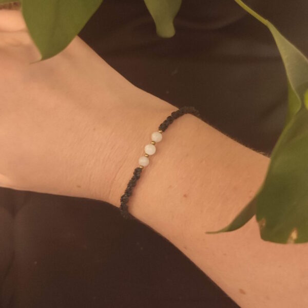 Cette photo représente un bracelet noir en micro macramé avec de la pierre de lune.